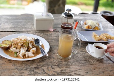 The famous traditional food from Indonesia, such as a vegetables salad with peanut sauce, a hot ginger drink and a origin coffee are served on a wooden table. - Powered by Shutterstock