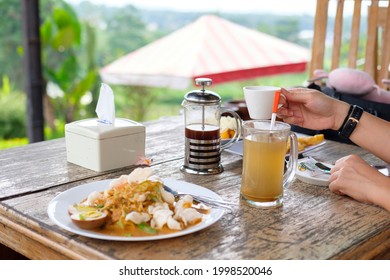 The famous traditional food from Indonesia, such as a vegetables salad with peanut sauce, a hot ginger drink and a origin coffee are served on a wooden table. - Powered by Shutterstock