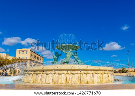 The famous Triton fountain, three bronze Tritons holding up a huge basin, in front of the City Gate in Valletta, sizable landmark fountain featuring multiple bronze tritons on a stone base, Valletta