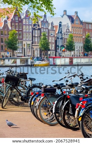Famous view of Amsterdam - parked bicycles and traditional houses on the Amstel river. Amsterdam, Holland, Netherlands, Europe