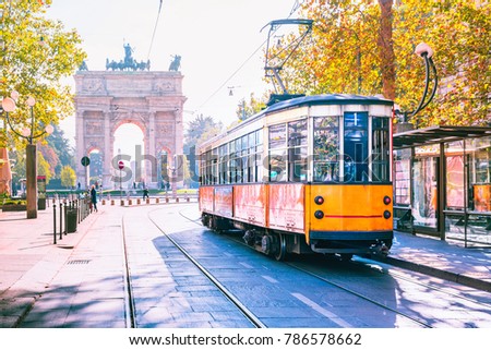 Famous vintage tram in the centre of the Old Town of Milan in the sunny day, Lombardia, Italy. Arch of Peace, or Arco della Pace on the background.