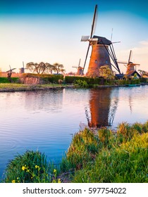 Famous windmills in Kinderdijk museum in Holland, UNESCO World Heritage Site. Colorful spring sunset in countryside. Splendid outdoor scene in Netherlands, Europe. Artistic style post processed photo.