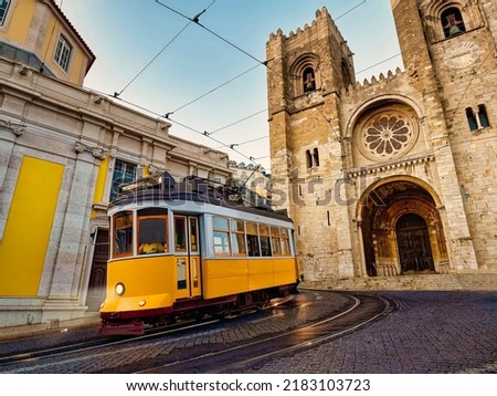 A famous yellow tram 28 passing in front of Santa Maria cathedral in Lisbon, Portugal at dusk or twilight