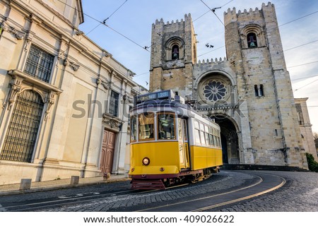 A famous yellow tram 28 passing in front of Santa Maria cathedral in Lisbon, Portugal
