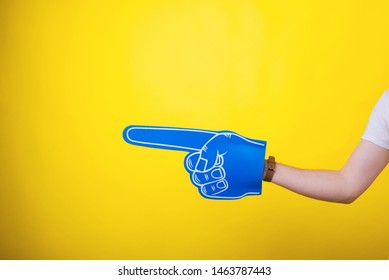 Fan finger foam pointing at copyspace over yellow background - Powered by Shutterstock