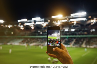 Fan hand with smartphone photographing football match. Using mobile phone camera at the stadium - Shutterstock ID 2154874333