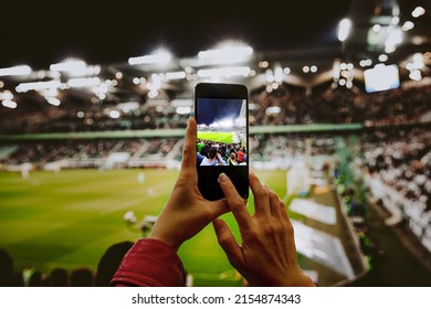 Fan hand with smartphone photographing football match. Using mobile phone camera at the stadium - Shutterstock ID 2154874343