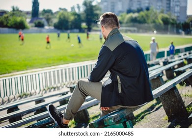 The fan watches the game of his favorite team. Athlete resting on a bench on a football field after a game. Football team training. - Shutterstock ID 2165000485
