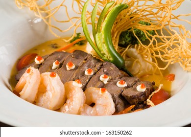 Fancy Asian Shrimp And Filet Mignon Served With Crispy Noodles And Vegetables On A White Plate.