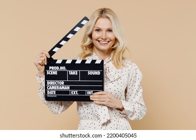 Fancy Cheerful Charming Elderly Gray-haired Blonde Woman Lady 50s Years Old Wears Pink Dress Holding Classic Black Film Making Clapperboard Isolated On Plain Pastel Beige Background Studio Portrait