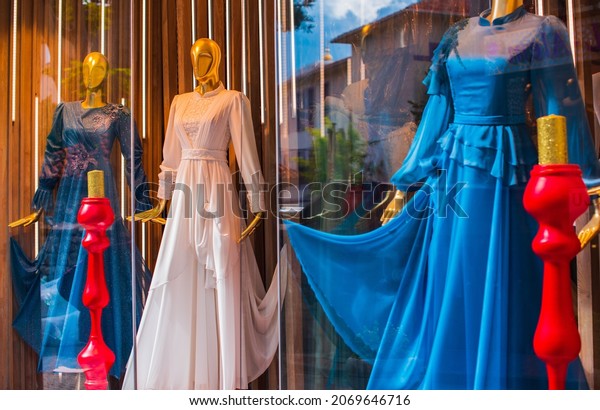 Fancy clothing on mannequins in a store in Arabic\
shops. Display of a clothing store, bright and fashionable window\
of modern fashion. Beautiful clothing in a luxury store window.\
Sale for people