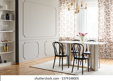 Fancy Dining Room Interior With Molding On A Gray Wall And Elegant Black Chairs Around A Marble And Golden Table