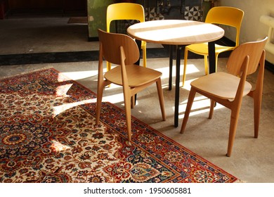 Fancy Dinning Room Interior. Wooden And Plastic Yellow Chairs By The Round Table, Colorfull Carpet On The Floor. Loft Desighn.