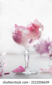 Fancy Drink In Wide Champagne Glass With Pink Flowers And Ice Cubes