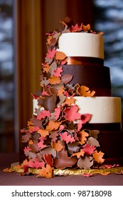 A Fancy Fall Themed Wedding Cake With Sugar Leaves Falling Down The Side