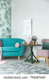 Fancy interior of a living room interior with a stylish pink flamingo painting hanging over a turquoise couch standing by an herb patterned wallpaper