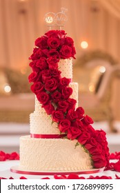 Fancy Modern White Wedding Cake With Gold Accents And Lush Red Rose Garland Cascading Down