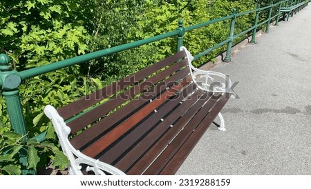 Fancy Parkbench close to green fence at sidewalk