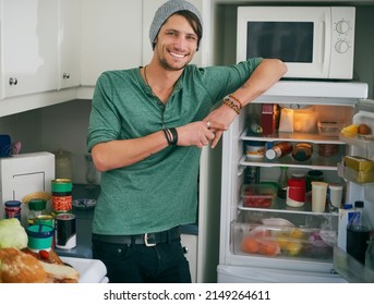 Fancy A Snack. Portrait Of A Smiling Young Man Standing By An Open Fridge In His Kitchen.