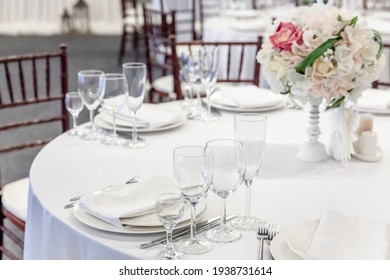 Fancy Table Set For Dinner With Flower Composition In Restaurant, Luxury Interior Background. Wedding Elegant Banquet Decoration And Items For Food Arranged By Catering Service On White Table