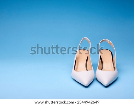Fancy white open-back pumps with pastel insoles with black outlines. Isolated on a gradient blue background with copy space on left and on top. Concept for modern and fashionable shoe store.