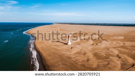 Fangar Lighthouse on remote sandy peninsula with Mediterranean coastline and dunes in the Ebro Delta aerial panorama.