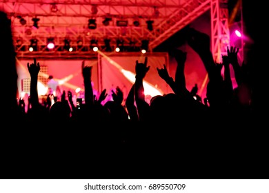  fans enjoy concert in the fan zone of hall during concert of  band. crowd of people silhouettes with their hands up. Selective focus of attention