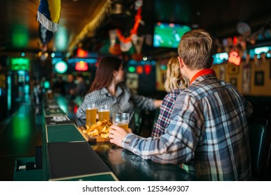 Fans With Glasses Of Beer At Counter In Sports Bar