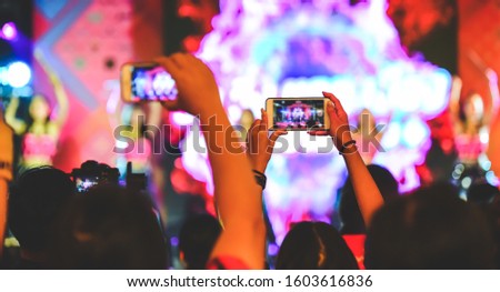 Fans are having fun, both taking pictures with the camera and mobile phone. Concert performer
