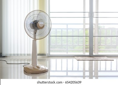 Fans placed in front of the curtains in the room.