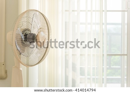 Fans placed in front of the curtains in the room.