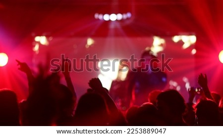 Fans Raise Hands and takes a photos in Front of Bright Colorful Strobing Lights on Stage.