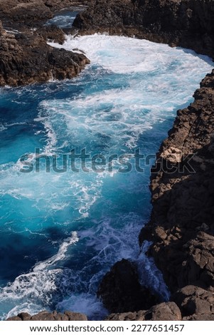 The fantastic bright blue colour of water in Buracona bay on the island of Sal, Cabo Verde. The amazing beauty of the ocean. Rocky cliffs and the Blue Eye cave of the Buracona reserve.