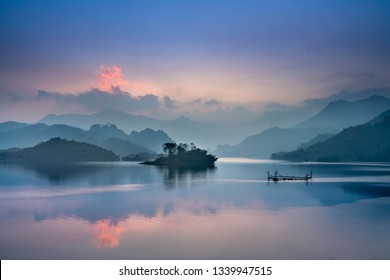 Fantastic clouds and sunset sky. Peaceful time. Colorful sky reflecting in the lake. Silhouette. Summer is coming. Beautiful peaceful scenery of mountain forest in Th.Lam Commune, T. Quang Province,VN