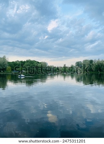 Fantastic cloudy sky reflection on the lake surface, trees silhouettes reflection on the lake, evening twilights lake in the park