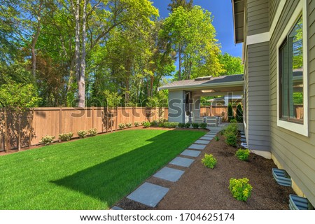 Fantastic new backyard with fresh landscape, fully fenced, with back porch, and large birch trees, steps and mulch.