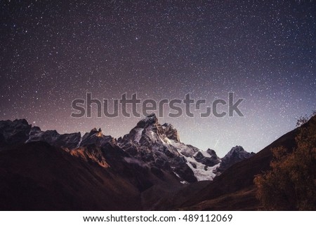 Fantastic starry sky. Autumn landscape and snow-capped peaks. Main Caucasian Ridge. Mountain View from Mount Ushba Meyer, Georgia. Europe.