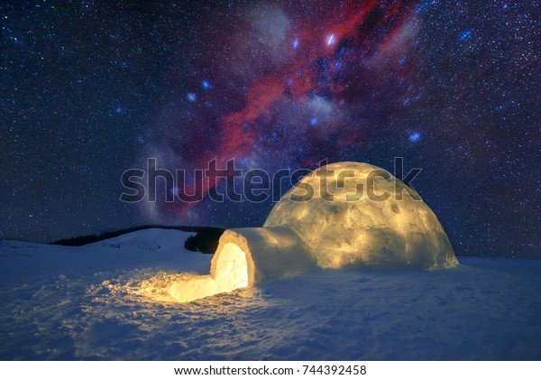 Fantastic winter landscape glowing by star light. Wintry
scene with snowy igloo and milky way in night sky. Carpathian
mountains. Santa house from snow,  ideal New Year and Christmas
background 