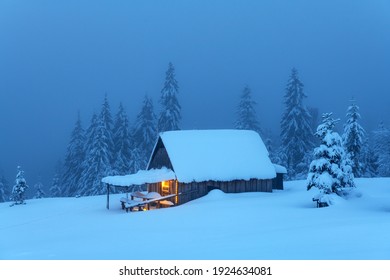 Fantastic winter landscape with glowing wooden cabin in snowy forest. Cozy house in Carpathian mountains. Christmas holiday concept - Powered by Shutterstock