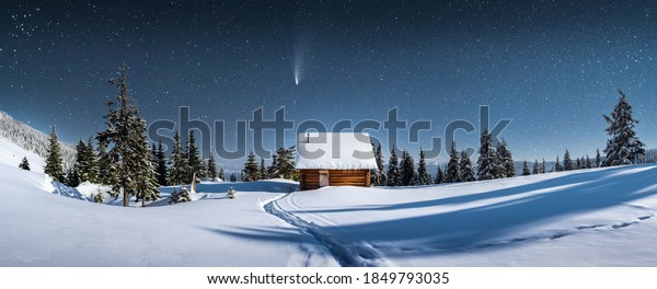 Fantastic winter landscape\
panorama with wooden house in snowy mountains. Starry sky with\
Milky Way and snow covered hut. Christmas holiday and winter\
vacations concept
