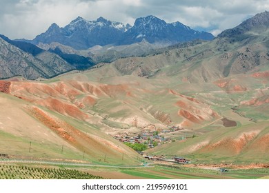 Fantastic Yadan landform landscape, red canyon rocky colorful scenic and old village, red mountain backgrounds. The sun shines down around terraced wheat fields. Qilian, China, Spring season