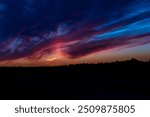 Fantastically abstract dark red blue sunset with a forest line on the horizon