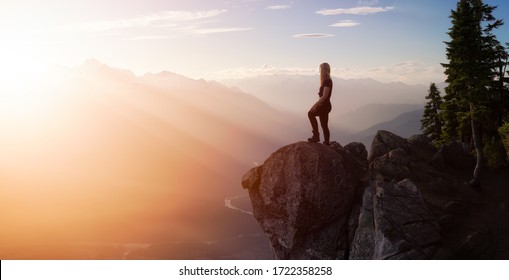 Fantasy Adventure Composite with a Girl on top of a Mountain Cliff with Dramatic Nature in Background during Sunset or Sunrise. Landscape from British Columbia, Canada. Panorama