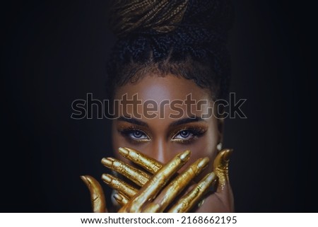 fantasy art portrait blue eyes close up, face african american woman. Professional golden metallic make-up shiny shadows. Hands in gold liquid drops flow. Fashion model girl. Studio black background