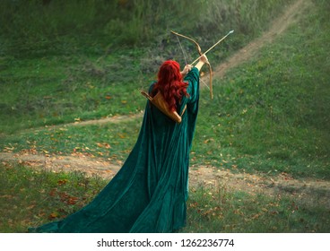 Fantasy Art Queen.Mysterious Silhouette Woman Shooter Medieval Lady Princess Mystical Warrior Holds Bow Arrow In Hands, Redhead Curly Hair Green Velvet Cloak Cape Vintage Clothes. Image Hunter, Back