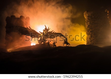 Fantasy battle scene with dragons attacking a medieval castle at night. Battle between dragon and heroic soldiers. Creative table decoration. Selective focus