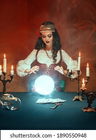 Fantasy beautiful gypsy girl, predicts fate, feel energy of crystal ball in dark gothic room. Mystical photo of old art vintage astrology. Fortune teller woman reading future on magical tarot cards.