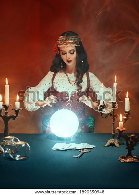 Fantasy beautiful gypsy girl, predicts fate, feel\
energy of crystal ball in dark gothic room. Mystical photo of old\
art vintage astrology. Fortune teller woman reading future on\
magical tarot cards.