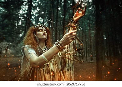 Fantasy. Fairy Forest Witch. An Ancient Shaman Woman With Spooky Burning Eyes Performs A Mystical Shamanic Ritual In A Gloomy Forest. Halloween. 