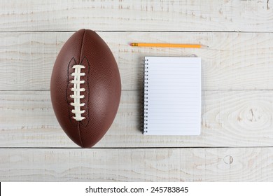 Fantasy Football Draft Still Life. A Pad And Pencil And An American Style Football On A White Wood Table In A Home Office.